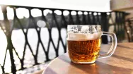 Picture of a tankard of beer on a wooden table in front of a railing